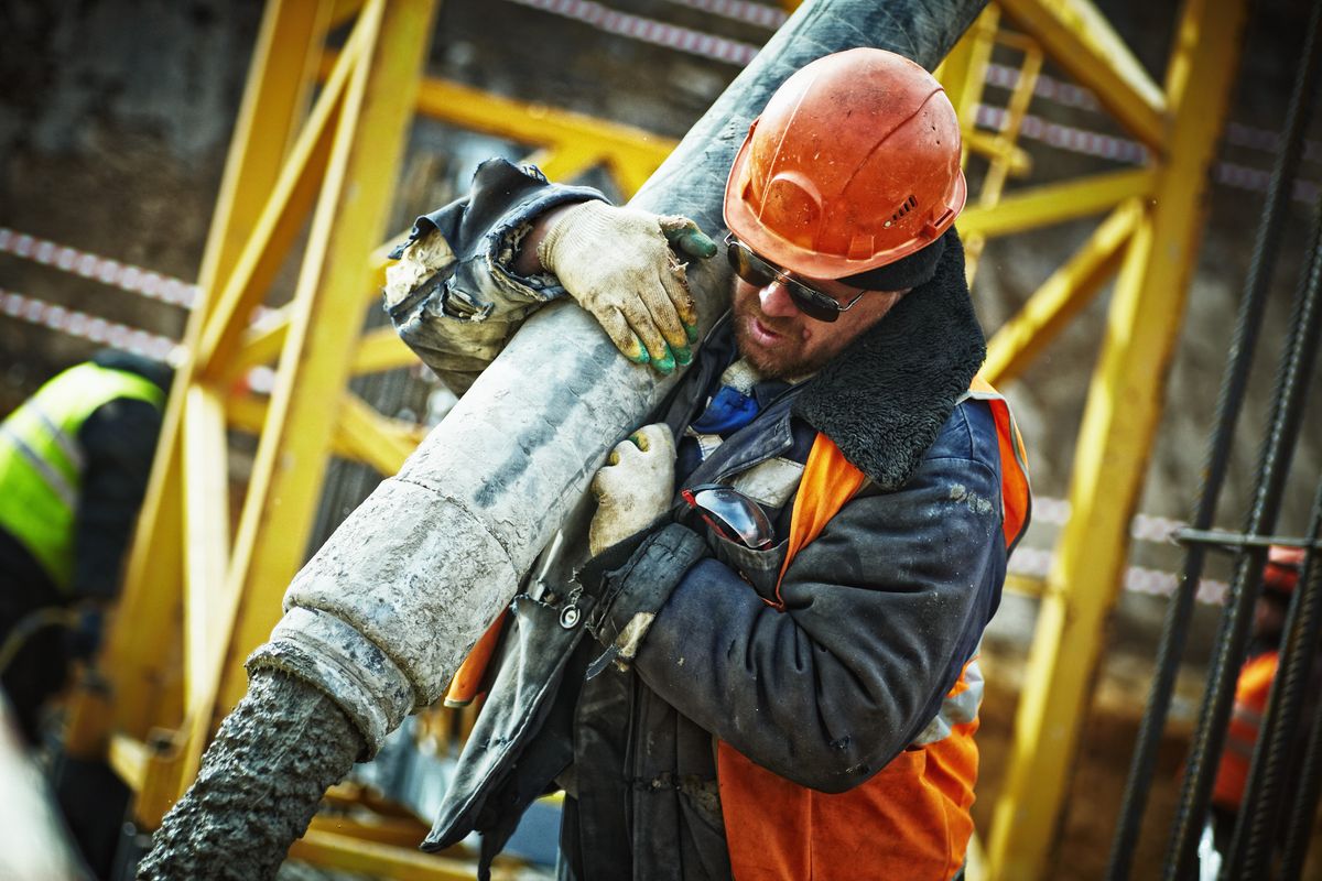 Worker in safety gear pumping concrete on a commercial job site